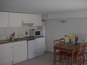 a kitchen with white cabinets and a wooden table with a dining room at Gîte LA GRANGE du Vialaron in Villard