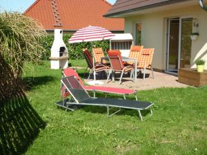 un patio con sillas, una mesa y una sombrilla en Ferienhaus Kozian en Kühlungsborn