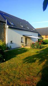 una casa blanca con techo solar en un patio en Chambres d'hôtes La Pinderie, en Val Couesnon