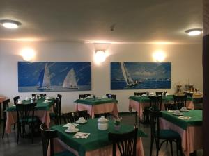 una sala da pranzo con tavoli e sedie verdi e barche a vela alle pareti di Hotel Plaza a Desenzano del Garda