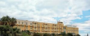 een groot geel gebouw met een bewolkte hemel erachter bij Excelsior Palace Hotel in Taormina