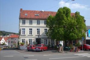 a red car parked in front of a white building at Hotel zur Eiche in Oberthal