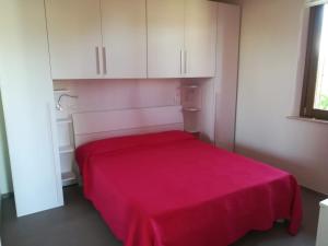 a red bed in a room with white cabinets at Tulipano Appartamenti in Marotta