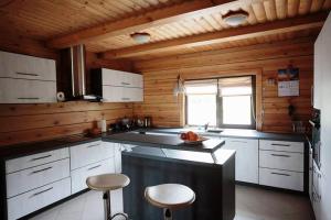 a kitchen with white cabinets and a counter with stools at Sodyba Pas Jelena in Rokiškis