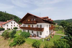 une grande maison sur une colline avec des gens assis dans l'herbe dans l'établissement Landhaus Altweck, à Wegscheid