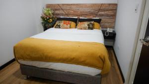 una camera da letto con un grande letto con una coperta gialla di Hotel Funza Real a Funza