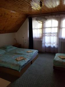 a bedroom with two beds and two windows at Tó úti Vendégház in Mezőtúr