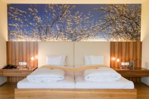 1 dormitorio con 1 cama con una pintura en la pared en Genusshotel Riegersburg, en Riegersburg