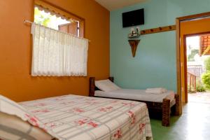 a bedroom with two beds and a tv on the wall at Pousada Quintal da Serra in Serra do Cipo