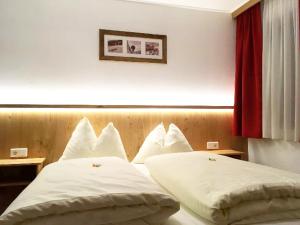 sypialnia z 2 łóżkami i białymi poduszkami w obiekcie Berghotel Lämmerhof w mieście Sankt Martin am Tennengebirge