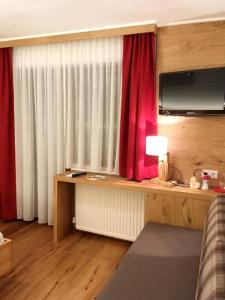 a room with a desk with a television and a red curtain at Berghotel Lämmerhof in Sankt Martin am Tennengebirge