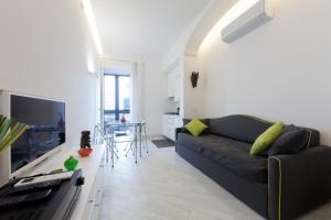 a living room with a black couch and a tv at Boutique House Fiò in Ischia