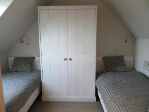a bedroom with two beds and a white cabinet at B&B 't Hannonshof in Nieuwpoort