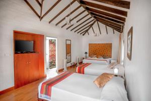 two beds in a room with a tv and two beds at Hotel Tata Premium in Pueblo Tapao
