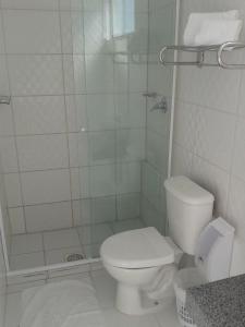 a white bathroom with a toilet and a shower at Dalle Hotel in Bagé