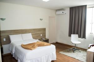 a bedroom with a white bed and a chair at Dalle Hotel in Bagé