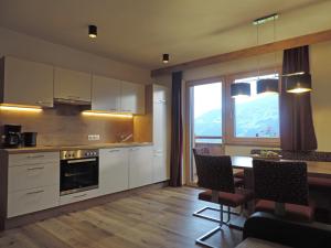 a kitchen with white cabinets and a table with chairs at Ritzerhof Apartments in Stummerberg