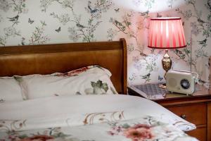a bedroom with a bed and a table with a lamp and a clock at Willa Karolinka Stróża - Pet Friendly in Myślenice