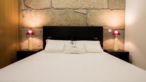 a bedroom with a large white bed with two lamps at Bugalha My Loft Douro 7 in Peso da Régua +7 photos