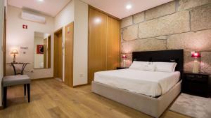 a bedroom with a large bed and a stone wall at Bugalha My Loft Douro 7 in Peso da Régua