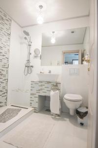 a white bathroom with a toilet and a sink at Hotel Merty in Constanţa