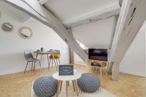 a room with two tables and chairs and a tv at Les Mansardes du Roi in Versailles