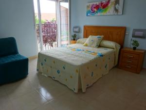 1 dormitorio con 1 cama, 1 silla y 1 ventana en La casa del veterinario, en Ataquines