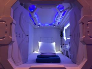a small room with a bed with blue lights at Passgo Digital Airport Terminal 3 Soekarno Hatta in Tangerang