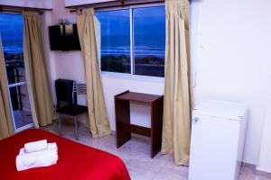 Una habitación con una cama roja y un escritorio y una ventana. en Hotel San Remo Majestic, en Mar de Ajó