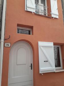 a orange building with a white door and a window at Maison de village in Bagnols-en-Forêt