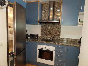 Una cocina con gabinetes azules y un refrigerador de acero inoxidable. en Marina 2, en Roses