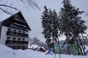 budynek w śniegu obok dwóch drzew w obiekcie Apartament W&J w Szklarskiej Porębie