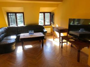 a living room with a black couch and a piano at Dworek Cieszyński in Cieszyn