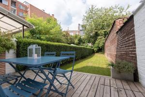 una mesa azul y sillas en una terraza de madera en La petite Naimette, en Lieja