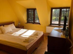 a bedroom with a bed and a desk and two windows at Dworek Cieszyński in Cieszyn