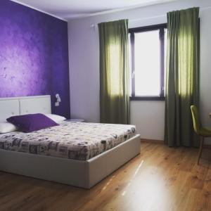 1 dormitorio con cama y pared púrpura en Il Gatto Stanco B&B, en Arona