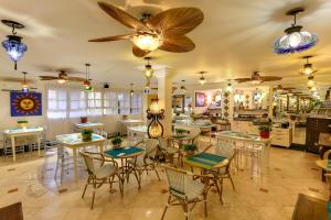 um restaurante com mesas e cadeiras e ventoinhas de tecto em Villas Jurerê Hotel Boutique em Florianópolis