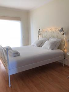 um quarto com uma cama branca e almofadas brancas em Mar e Arte em Olhão