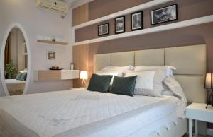a bedroom with a large white bed with two green pillows at Haris Apartment Tirana no.2 in Tirana