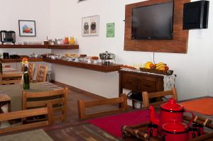 uma sala de jantar com uma mesa e uma televisão na parede em Pousada Encantos do Peró em Cabo Frio
