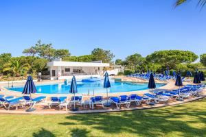 a pool with blue chairs and umbrellas at Victory Village 3A in Quinta do Lago