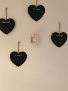 four black hearts hanging on a wall with a bird cage at Bari Lory’s Home in Bari