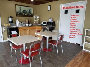 a kitchen with two tables and red chairs in a room at The Simplicity Inn in Marshfield