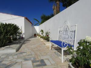 a bench sitting on a stone walkway next to a white wall at Casa da Horta in Aroeira