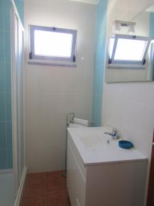 uma casa de banho com um lavatório e uma janela em Casa da Horta em Aroeira