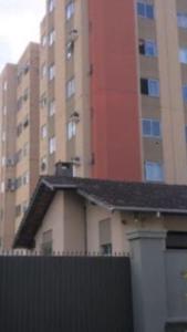 a building with a fence in front of some tall buildings at Apartamento: Acomodação mobiliada e completa in Blumenau