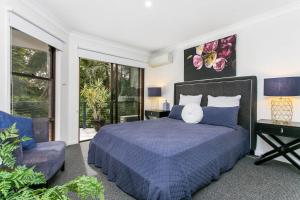 Un dormitorio con una cama azul y una silla. en Calinda Sol 2 @ Clarkes Beach, en Byron Bay