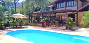 a house with a swimming pool in front of a house at Arara Azul in Nova Friburgo