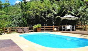 a swimming pool with an umbrella and a table and chairs at Arara Azul in Nova Friburgo
