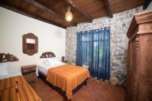 a bedroom with a bed and a stone wall at VILLAS JUCANYA Super Higienizadas in Panajachel